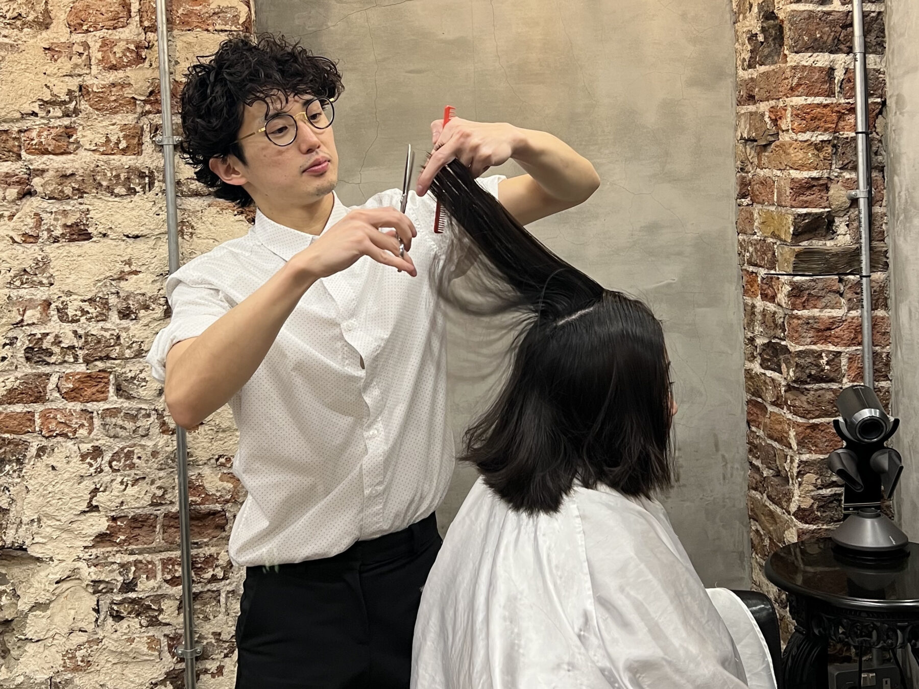 A side view of a woman getting a haircut, highlighting natural hair flow and volume at the crown