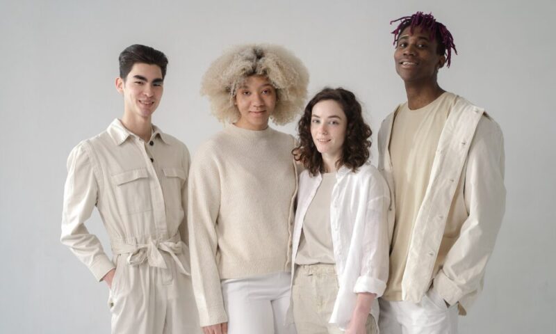 A portrait of four individuals with diverse hair textures, skin tones, and ages standing together with natural expressions. The photo reflects a message of embracing individuality.