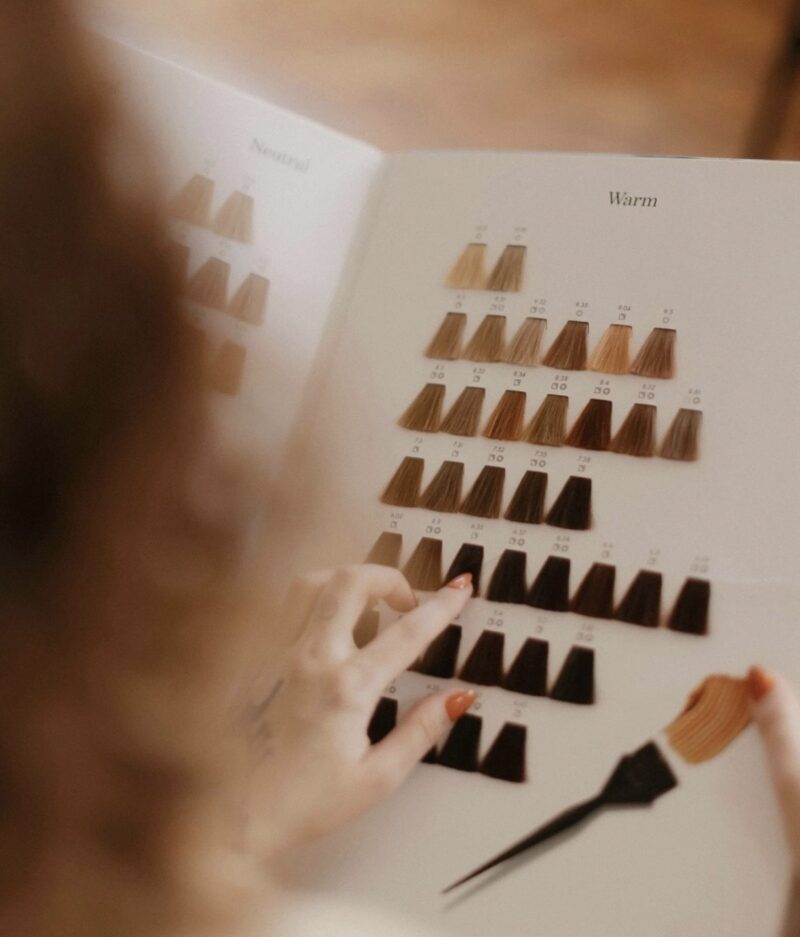 A hairdresser consulting with a client while looking at a color chart for hair shades