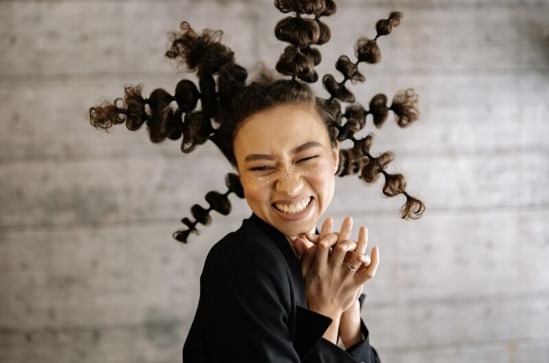 A woman enjoying her uniqueness with bold curly hair and a big smile