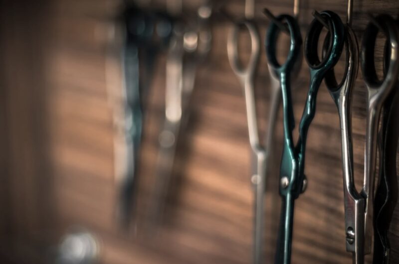 A row of professional hairdressing scissors hanging neatly in a salon