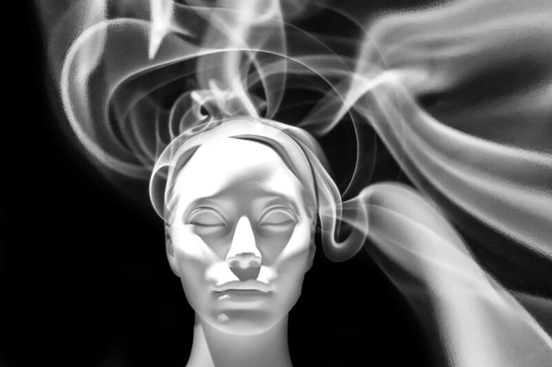 An abstract art image of a white mannequin head with smoke-like curves rising from it, symbolizing hair design or the flow of thought in a surreal style.