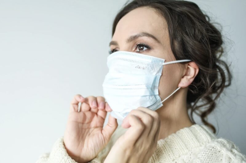 Side view of a woman wearing a face mask, showing her eyes and hairstyle