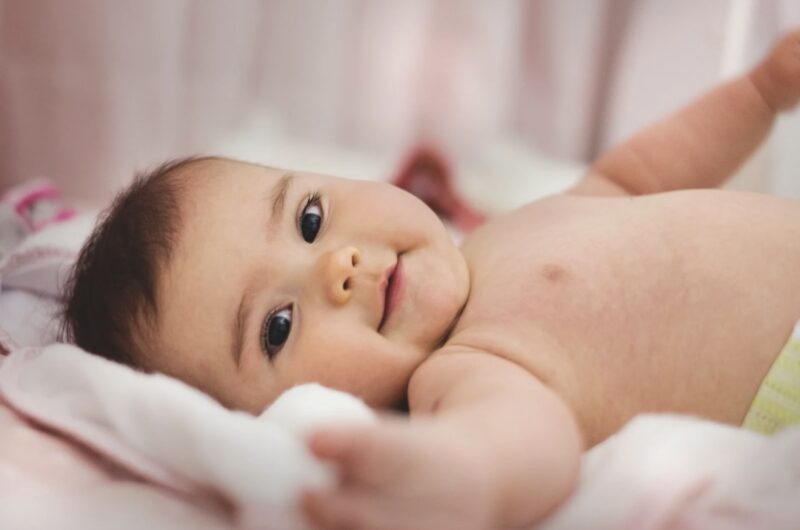 A smiling baby lying on a bed