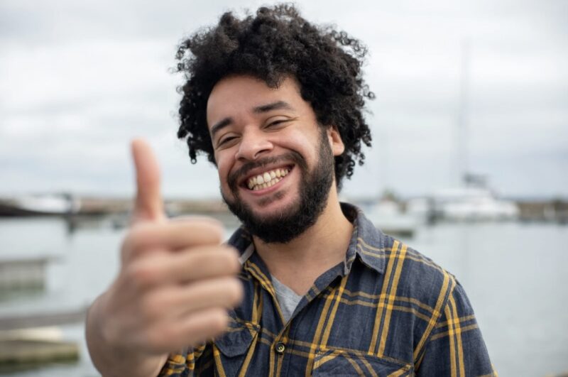 A smiling man giving a thumbs-up, expressing positivity and satisfaction.