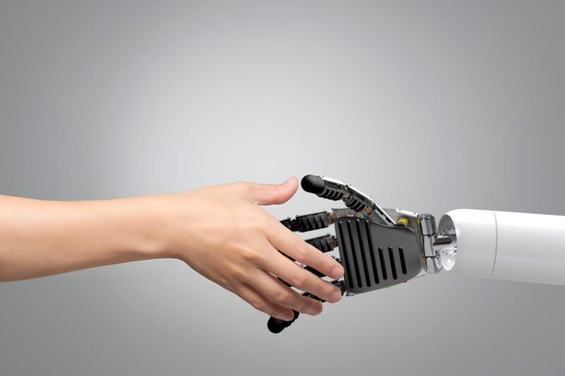 A human hand shaking hands with a robotic hand, symbolizing the coexistence of technology and humanity.
