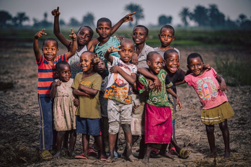 Children smiling and hugging each other, joyfully playing in nature.