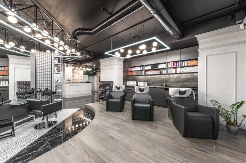 Modern and stylish hair salon interior with shampoo stations, cutting chairs, bright lighting, and neatly arranged haircare products.