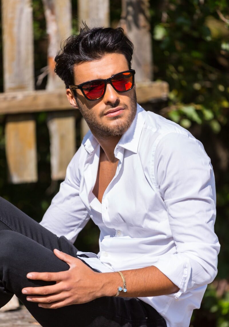 A man wearing a white shirt and sunglasses relaxing outdoors