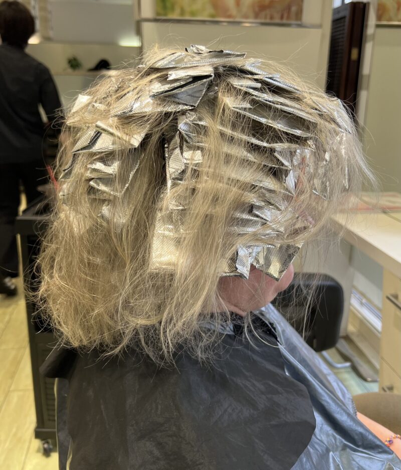 白髪をぼかすために頭皮に薬剤を付けず、アルミホイルを使ったハイライト施術を行っている途中の後頭部の様子