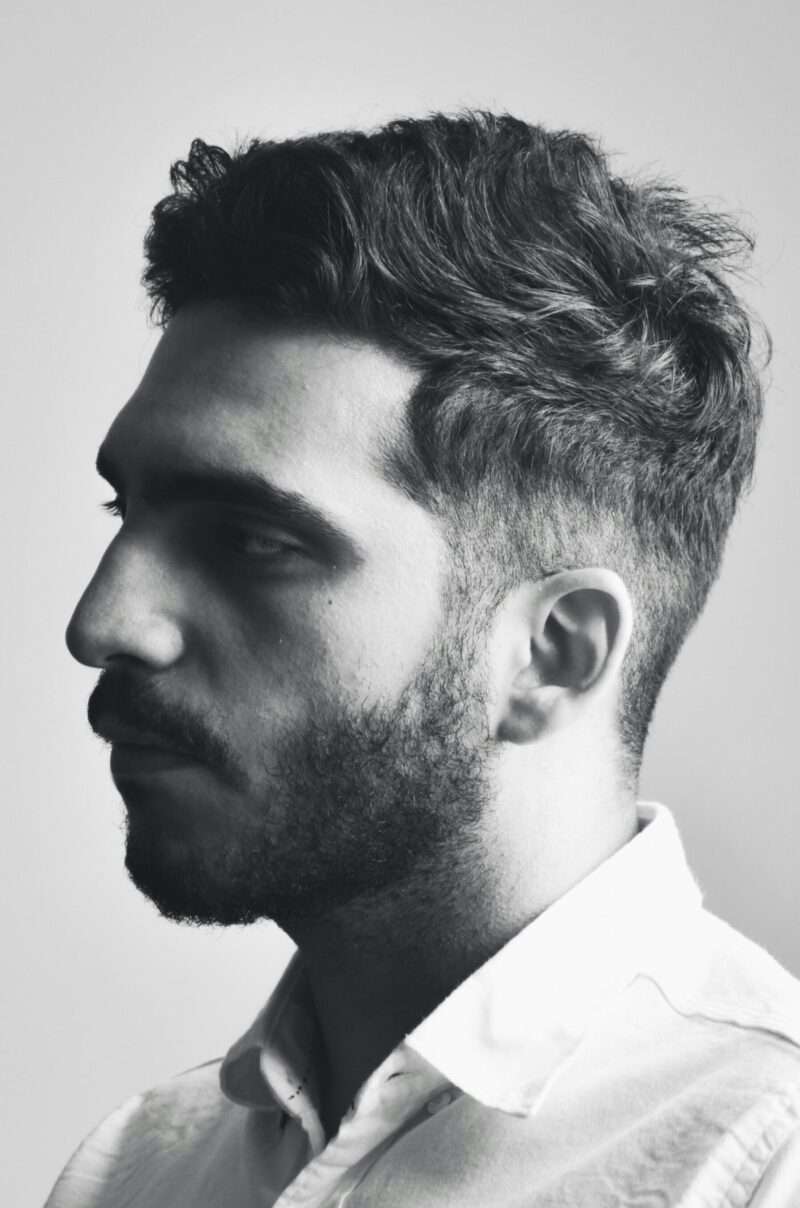 Clean men’s hairstyle with natural textured top and faded sides (side view)
