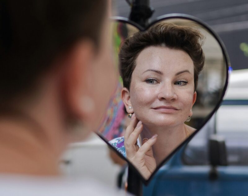 A woman checking her short hairstyle in the mirror. The look has natural volume and control, creating a clean and polished appearance.